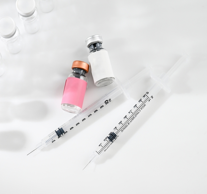 Syringes and labeled peptide vials on white surface representing personalized hormone and metabolism therapy treatments