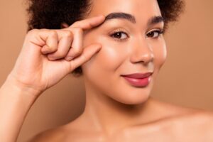 Woman highlighting under-eye area, representing comparison between Botox and fillers for smoother, youthful-looking skin