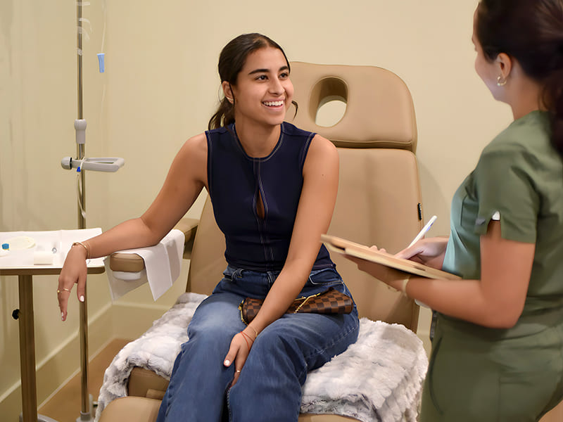 Young woman receiving IV therapy while consulting with a professional, highlighting supportive treatment for stress and anxiety management