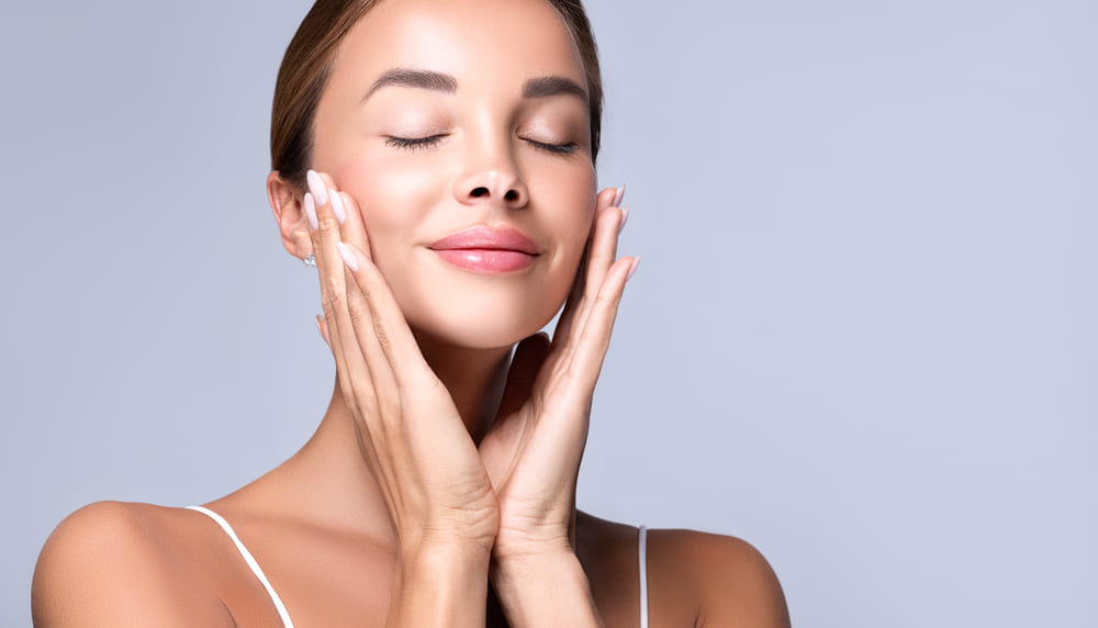 Woman with clear skin touching face representing safe use of Botox and Dysport with mild side effects when administered properly